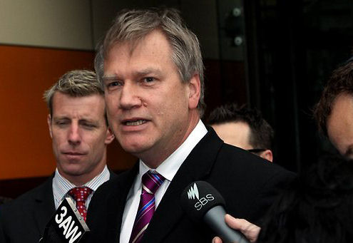 Andrew Bolt defends himself outside court, while the guy behind is inspired to sleep...