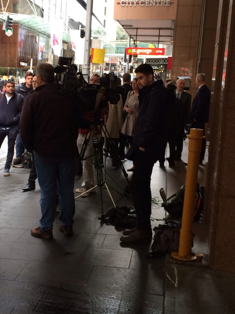 Media crowd the street outside the commission